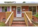 A charming brick home welcomes you with a wooden porch and a delightful white door at 107 Glosson Cir, Carrboro, NC 27510