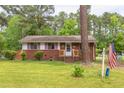 A single-story brick home showcases pink shutters and is complemented by a manicured lawn and mature trees at 107 Glosson Cir, Carrboro, NC 27510