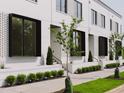 Charming townhome exterior featuring crisp white brick, black framed windows, and landscaped front yards at 1302 Chamblee Hill Ct, Raleigh, NC 27608
