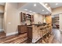 Custom basement bar featuring wood paneling, brass barstools, a granite countertop, and custom shelving at 1308 Green Oaks Pkwy, Holly Springs, NC 27540