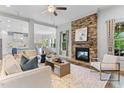 Inviting living room features a stone fireplace, a ceiling fan, and views into the kitchen and dining area at 1308 Green Oaks Pkwy, Holly Springs, NC 27540