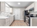 Bright kitchen featuring modern appliances, white cabinetry, and durable laminate flooring at 1628 Briarmont Court Ct, Raleigh, NC 27610