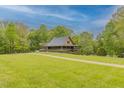 Scenic view of a well-maintained country estate with a charming metal-roof home, and a vast green lawn at 169 Country Brooke Lane Ln, Roxboro, NC 27574