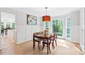 Bright dining area featuring wood floors, an elegant chandelier, and views of the private, wooded backyard at 2169 Rawls Church Rd, Angier, NC 27501