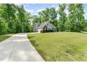 Single-Gathering home features a spacious driveway and verdant lawn, bordered by dense, mature trees at 315 Copper Ridge Dr, Sanford, NC 27330