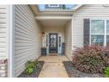 Close-up view of the home's entryway, featuring a dark-stained door, landscaping, and charming details at 3248 Castlerock Dr, Burlington, NC 27215