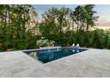 Relaxing backyard pool with travertine patio, lush landscaping, and lounge chairs at 325 Forest Bridge Rd, Youngsville, NC 27596