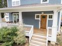 Inviting front porch features a wooden deck with white railings, and a wooden front door at 408 Jerome Rd, Durham, NC 27713