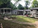 Expansive backyard with a covered patio, white pergola, and colorful flowerbeds creating a serene outdoor space at 5002 Wickham Rd, Raleigh, NC 27606
