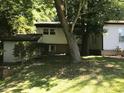 Exterior view of the home showing a partial basement and well-shaded surroundings at 5002 Wickham Rd, Raleigh, NC 27606