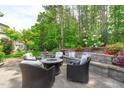 Landscaped backyard features a stone patio with an outdoor seating and a fire pit at 525 Morning Oaks Dr, Holly Springs, NC 27540