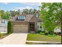 Charming stone home features a manicured lawn, two-car garage, and covered front porch at 525 Morning Oaks Dr, Holly Springs, NC 27540