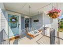 Inviting front porch featuring a swing, hanging flower basket, and a blue front door at 636 Copper Beech Ln, Wake Forest, NC 27587