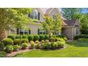 Landscaped front yard with mature trees, shrubbery, and a brick-laid walkway to the front door at 7212 Donneeford Rd, Wake Forest, NC 27587