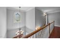 Elegant staircase with stained-glass window, chandelier, and hardwood floors adding a touch of classic charm at 7212 Donneeford Rd, Wake Forest, NC 27587