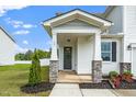 Charming front porch with stone accents, a dark front door, and beautifully landscaped flowerbeds at 73 Windswept Way, Fuquay Varina, NC 27526