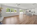 Open-concept living room with wood floors, many windows and white kitchen with island and seating at 73 Windswept Way, Fuquay Varina, NC 27526