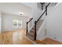 Carpeted staircase with white and black railing leading to the upper level and hardwood floors at 9117 Meadow Mist Ct, Raleigh, NC 27617