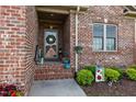 Inviting front porch with brick steps, flowerpots and decorative welcome sign at 928 Arrowhead Ln, Mebane, NC 27302