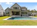 Back exterior with in-ground pool, covered patio, outdoor kitchen, and manicured lawn at 949 Harrison Ridge Rd, Wake Forest, NC 27587