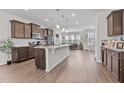 Open-concept kitchen boasts granite countertops, stainless steel appliances, wood cabinets, and wood-look flooring at 987 Parkstone Towne Blvd, Knightdale, NC 27545