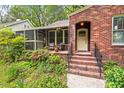 Close up of the brick home with a well-manicured lawn, and a cozy screened-in porch at 1113 Alabama Ave, Durham, NC 27705