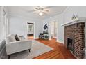 Living room with a brick fireplace, hardwood floors, neutral-toned walls, and ample natural light at 1113 Alabama Ave, Durham, NC 27705