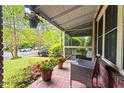Cozy screened-in porch with seating and hanging flowers, overlooking a lush front yard at 1113 Alabama Ave, Durham, NC 27705
