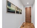 Hallway with hardwood floors, modern art, and a sleek wooden door creating an inviting entrance at 112 Meadowbrook Dr, Chapel Hill, NC 27514