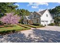 Charming white home with manicured landscaping, mature trees, and a gravel driveway, creating a picturesque setting at 2908 Stubble Field Dr, Raleigh, NC 27613