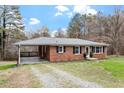 Brick home featuring a covered carport, mature trees, and well-kept landscaping at 3402 Pat Tilley Rd, Bahama, NC 27503