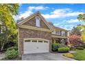 Beautiful home exterior featuring a stone garage, brick accents, a well-manicured lawn, and lovely landscaping at 3824 Laurel Hills Rd, Raleigh, NC 27612