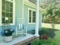 Cozy front porch detail with rocking chair, potted flowers, and a view of the home's light blue siding at 4793 Overhills Rd, Spring Lake, NC 28390