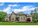 Stately stone and brick home with lush green lawn, manicured bushes and stone walkway at 628 Carolina Crossings Dr, Apex, NC 27523