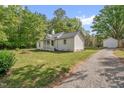 Quaint home featuring an outbuilding along with a gravel driveway and green lawn at 701 Oakwood St, Mebane, NC 27302