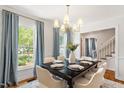 Sunlit dining room features elegant chandelier, dining set for six, and soothing blue drapes at 8504 Boot Ct, Raleigh, NC 27615