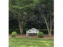Serene garden view featuring a white bench nestled between trees and manicured shrubbery at 9301 Brookton Ct, Raleigh, NC 27615