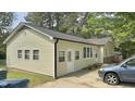 Side view of a house with yellow siding, showcasing the driveway and well-lit windows and landscaped yard at 1011 Wyldewood Rd, Durham, NC 27704