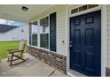 Inviting front porch with rocking chair, brick accents, and a dark blue front door at 105 Chandon Dr, Princeton, NC 27569