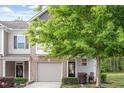 Inviting townhouse with an attached garage, manicured lawn, and mature shade tree at 11 Grifton Pl, Durham, NC 27704