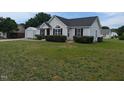 Charming single-story home with a well-manicured lawn, black shutters, and a detached garage at 111 Shadow Bend Ln, Selma, NC 27576