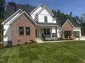 New home with white siding and red brick, showcasing a two-car garage and well-manicured lawn on a sunny day at 123-125 Ottawa Dr., Louisburg, NC 27549