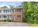 Two-story townhouse with brick facade, black shutters, and a small yard near a lush green forest at 1903 Malone Rd # E, Burlington, NC 27215