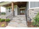 Inviting front porch with stone steps and elegant black railing details at 2 Deer Run Trl, Hillsborough, NC 27278