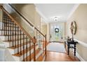 Elegant foyer with hardwood floors, staircase, and decorative lighting and a glass front door at 220 Lakecroft Pl, Fuquay Varina, NC 27526