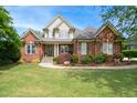 Inviting two-story brick home showcasing a well-manicured lawn, and classic architectural details at 220 Lakecroft Pl, Fuquay Varina, NC 27526