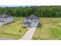 Expansive aerial view of a two-story home with a long driveway, surrounded by green lawns and woods at 234 Robert Howe Dr, Fuquay Varina, NC 27526