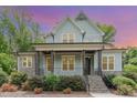 Charming home with stone accents, a covered porch, and meticulous landscaping under a vibrant sunset sky at 251 Gentry Dr, Pittsboro, NC 27312