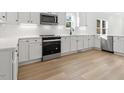 Bright kitchen featuring white cabinetry, stainless steel appliances, light wood floors, and modern countertops at 431 Longfellow St, Fuquay Varina, NC 27526