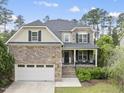 Charming two-story home featuring a stone facade, front porch, attached garage, and landscaped front yard at 449 Sandy Whispers Pl, Cary, NC 27519